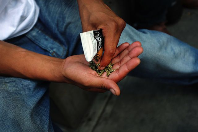 A man prepares to smoke K2 or 'Spice', a synthetic marijuana drug, along a street in East Harlem on August 5, 2015 in New York City